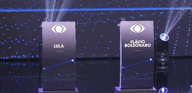 Lula e Flávio Bolsonaro se enfrentam neste domingo em debate da Band em São Paulo